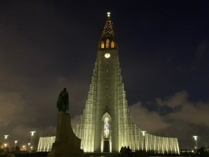 I passed Hallgrimskirkja on the way to the pool, a huge concrete Space Shuttle-shaped church inspired by basalt columns. Here it's lit in yellow-tinted light against a dark blue sky with some clouds low on the horizon behind it.