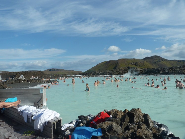 View from the edge of the Blue Lagoon, showing blue water set among low lava mountains.