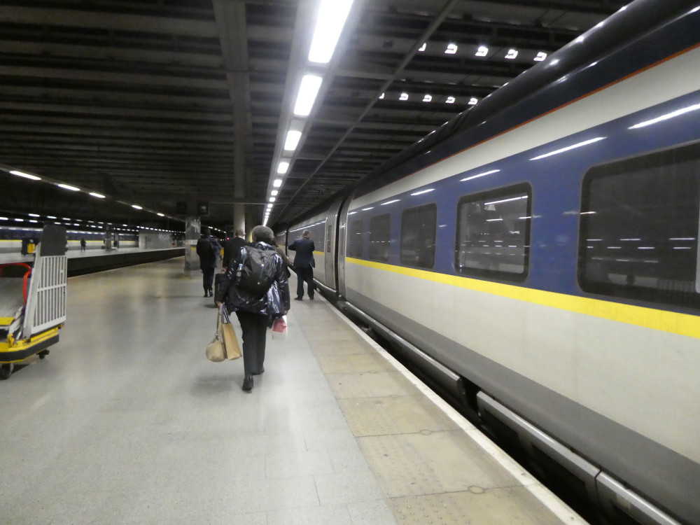 Walking up the Eurostar platform at St Pancras, with the train alongside me. It's a grey train with a yellow stripe under the windows and a long blue stripe around the windows.
