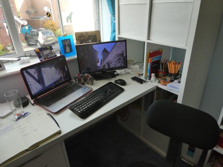 A desk with a laptop and a second monitor on it, attached at one end to a Kallax shelving unit.
