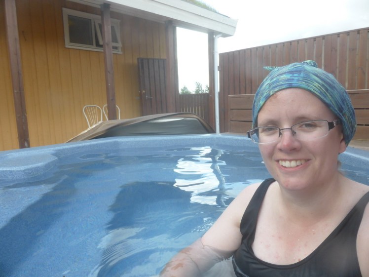 Me, with a buff tied around my hair to prevent contaminating the water with orange hair dye, sitting in a hotpot on a campsite looking very pleased with the whole thing.