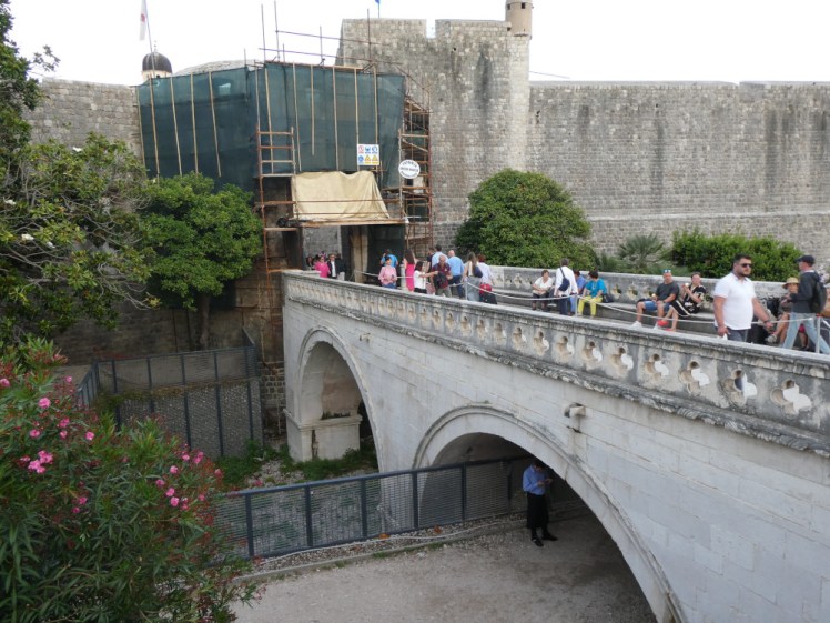 Pile Gate bridge, not as packed with people as the square I'm standing in. It's a stone bridge over a path and a park, leading directly into the huge imposing stone walls behind.