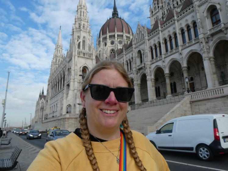 A selfie in a yellow jumper with the Gothic Hungarian Parliament Building behind me.