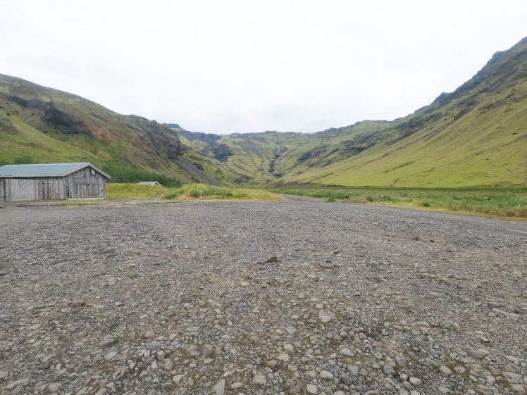 The unassuming and unmarked car park - a big patch of grey gravel facing the enclosed green valley.