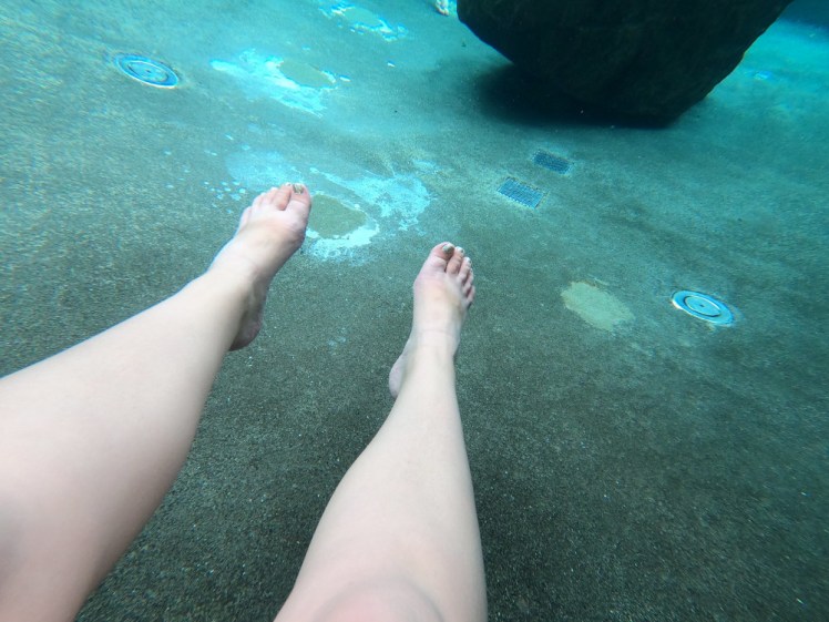 My feet and legs stuck out in front of me in bright turquoise water.