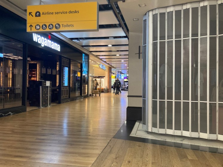 Heathrow closed and deserted at 5am, with grids over shops and only a few travellers in the distance.