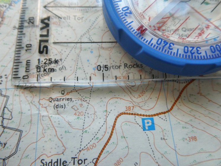 Close-up of compass and map. I'm using the scale on the edge of the compass to measure a blue grid box on the map. You can't actually see the 1km line because it's just hidden under the blue bezel.