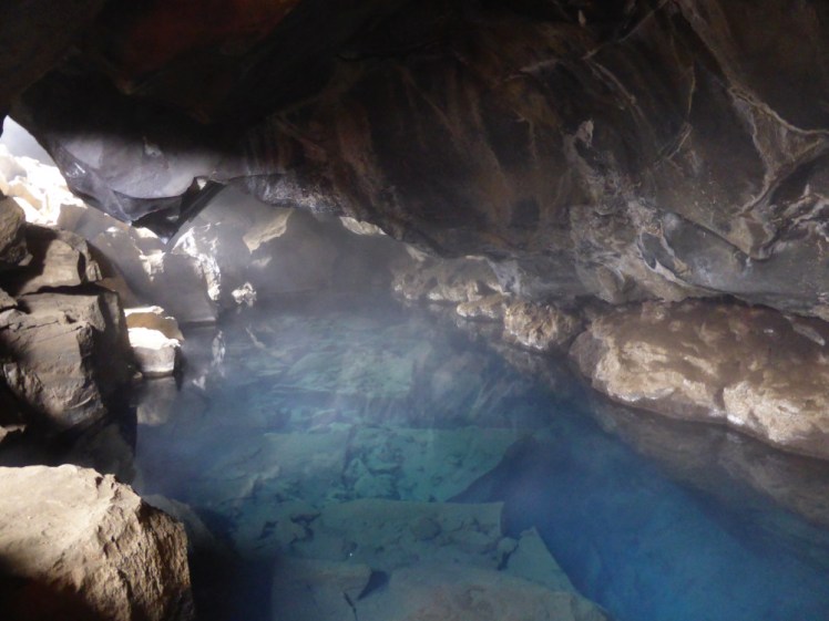 Grjótagjá, a cave shaped like a ridge tent, with half the ceiling collapsed into the bright blue steaming water which floods the cave.