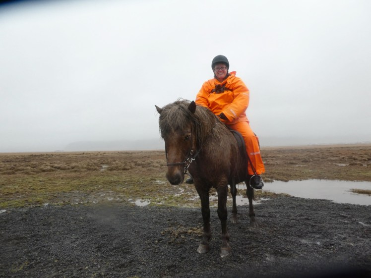 It's a wet day with the cloud touching the horizon behind me. I'm sitting on a small bedraggled brown horse, wearing a bright orange rubbery waterproof suit and a helmet, wearing my GoPro on a chest harness.