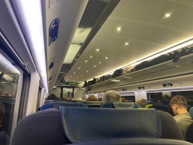 Inside the Eurostar, the view forward over my seat. The lighting is slightly yellow and you can see a few heads.