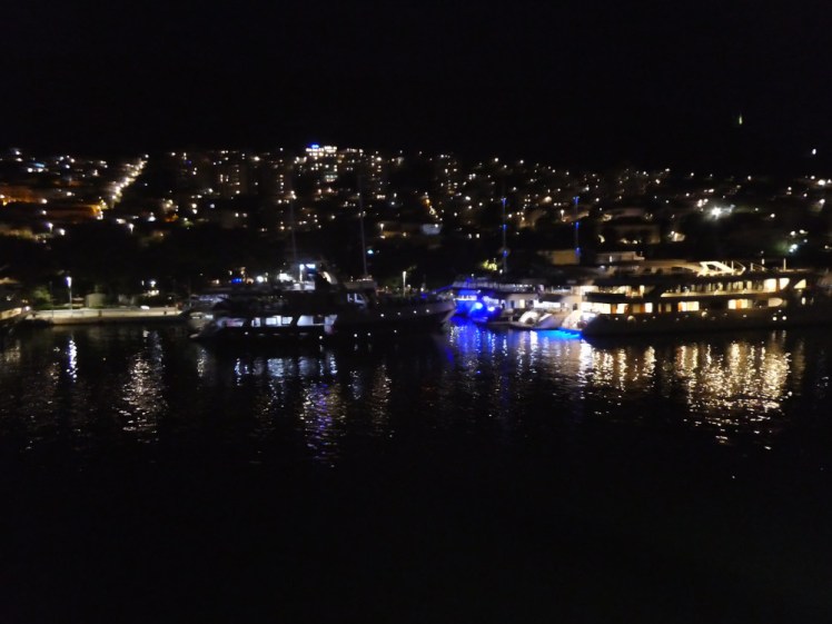 The lights of Gruz, going straight up the side of the mountain and stopping abruptly, while pleasure boats reflect in the water of the port.