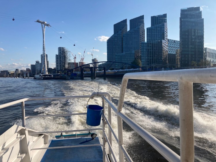 A view from the back of the Clipper as it zooms away from the glass towers of North Greenwich, leaving a huge wake behind.