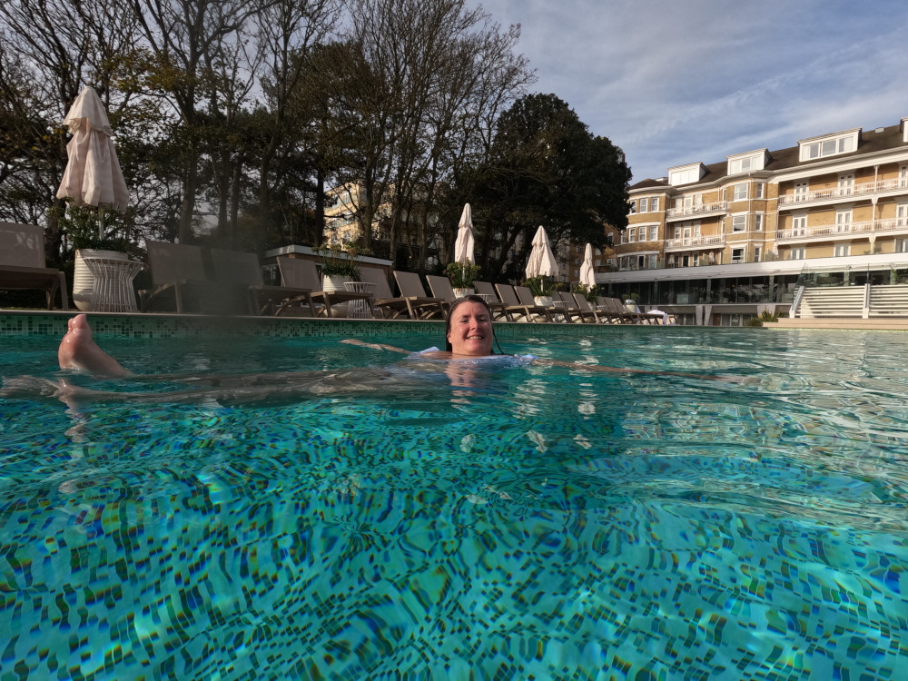 My sister lounging in the water, which is gorgeously green-blue, very clear, showing off tiny tiles and with the sun glinting on it despite it being November.