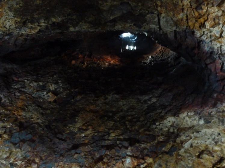 A photo taken from somewhere inside a volcano's empty magma chamber, looking up at the tiny hole in the ceiling where I descended in a window washer's basket. It's all a bit more greyish-yellowish than I might expect but otherwise looks exactly like you'd imagine the inside of a volcano to look.