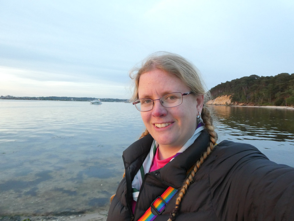 A selfie on the beach just as sunset turns my face golden-pink. It's chilly enough that I'm wearing my down jacket but you can make out my Brownsea Island neckerchief and pink t-shirt underneath.