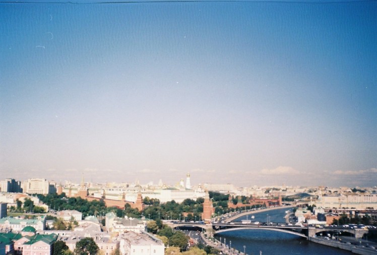 The Moscow skyline from the roof of the Cathedral of Christ the Saviour with the Kremlin occupying much of the centre of the picture. The sky is bright blue in the top corners but there's a kind of pink circle over most of it and the colours are definitely a bit off.