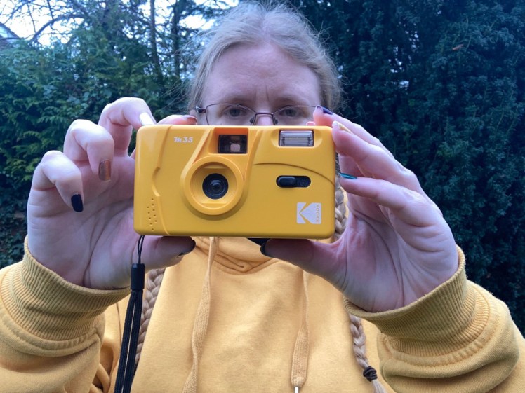 Me again, this time holding out a yellow plastic film camera in front of me. It has a black switch for sliding the flash on or off.
