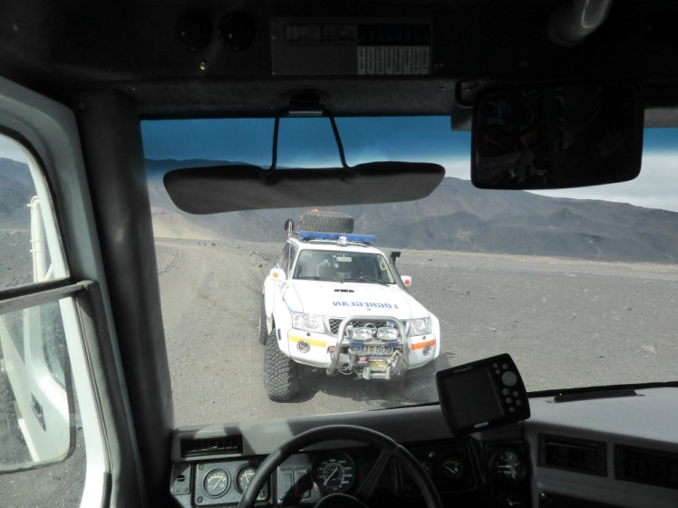 A police 4x4 in a pumice desert with a volcano in the background, as seen through the front window of our jeep. Its occupants are checking that our driver has all the paperwork to be driving tourists around the Highlands (he does).