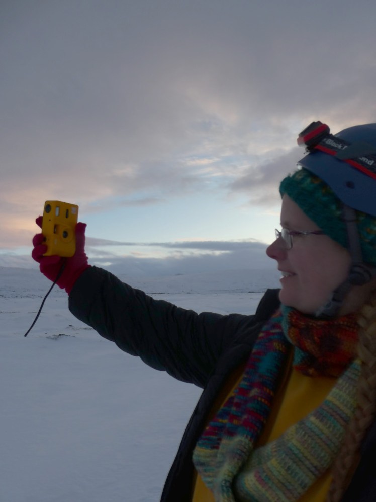 Me in Iceland, draped in colourful knitwear, taking a double selfie - I'm using my digital camera to take a photo with my left hand of me taking a photo of myself with my yellow film camera with my right hand.