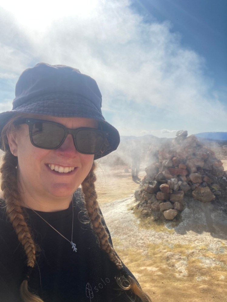Me in a faded blue bucket hat, standing by a pile of rocks that's been firing steam like an overboiled kettle for decades if not centuries.
