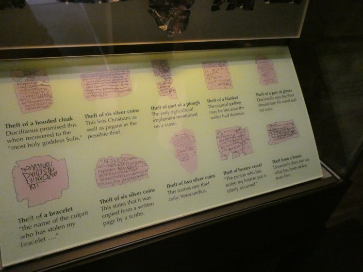 A panel showing sketches of various curse tablets with explanations of what they say on them.