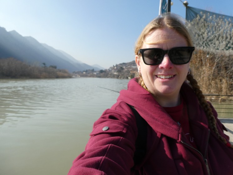A selfie down by a fairly wide river in Mtskheta, Georgia, wearing my red pocket hoodie.
