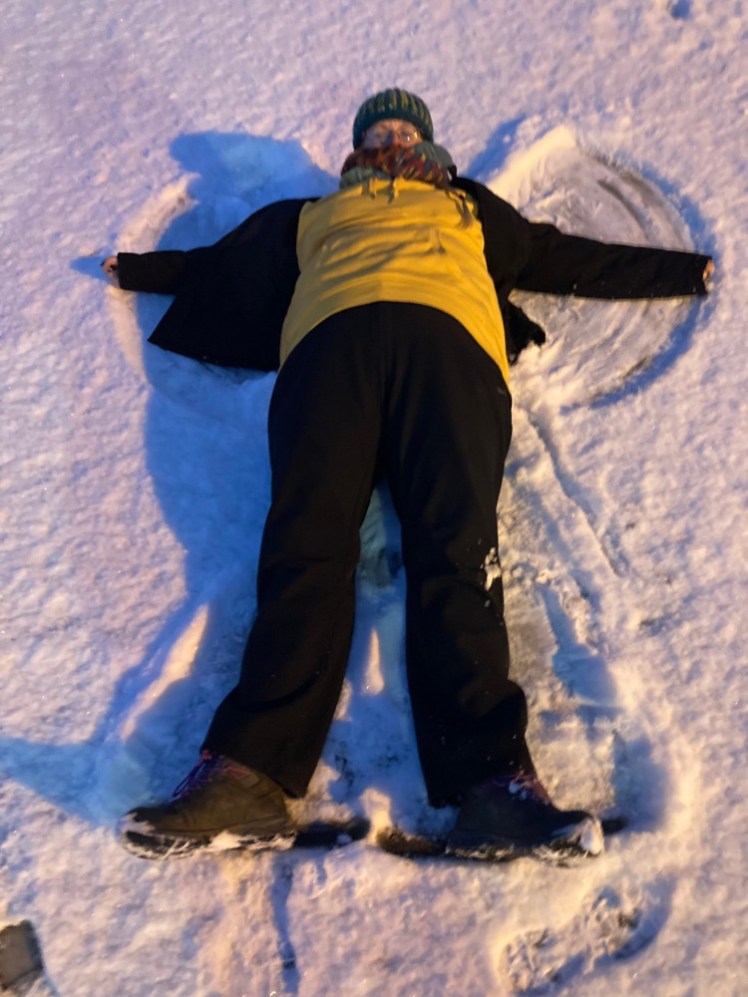 Lying in the snow in a car park, making a snow angel while wearing my yellow thermal top.