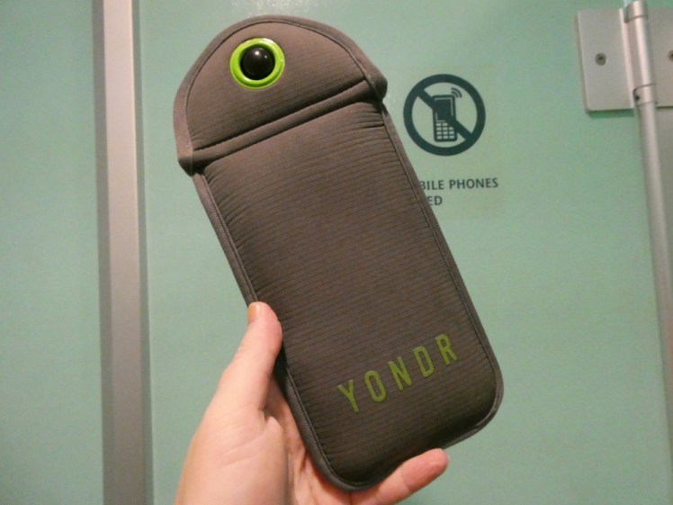 A grey pouch with a green circle at the top of the two flaps that open for insertion of phone. This is currently locked and I took it in the old-fashioned way with my camera.