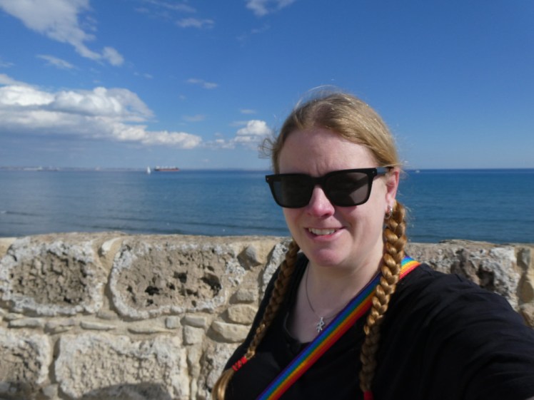 On top of a medieval fortress with the Mediterranean behind me, wearing my big black polarised prescription sunglasses.