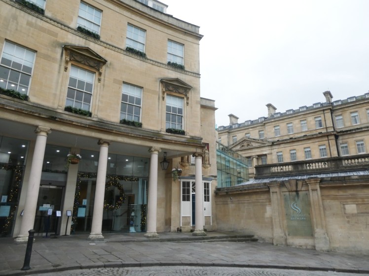 The frontage of Thermae Spa, a yellow stone Georgian-style building with columns holding up a small roof over the entrance.