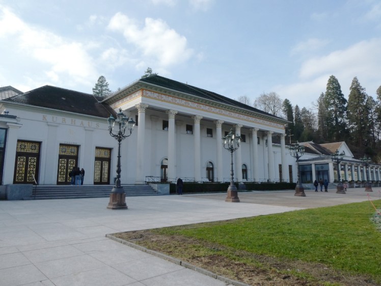 Baden-Baden's Casino, a white building with columns all along the front, murals above them and ornate gold-painted doors in the adjoining Kurhaus.