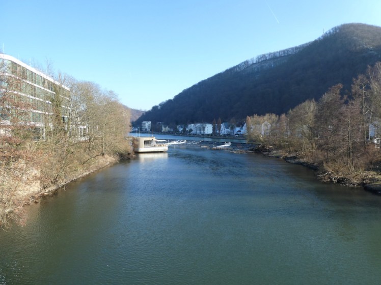 A view up the river. There's a weir in the middle and n the left is a small wooden structure over the river itself. This is the sauna.