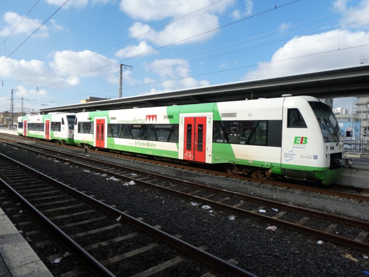 A two-car train parked at Schweinfurt. It's mostly white with red doors, a green stripe along the bottom and a green wedge surrounding the doors. This was one car when it left Bad Kissingen but has connected to the second car now it's at Schweinfurt.