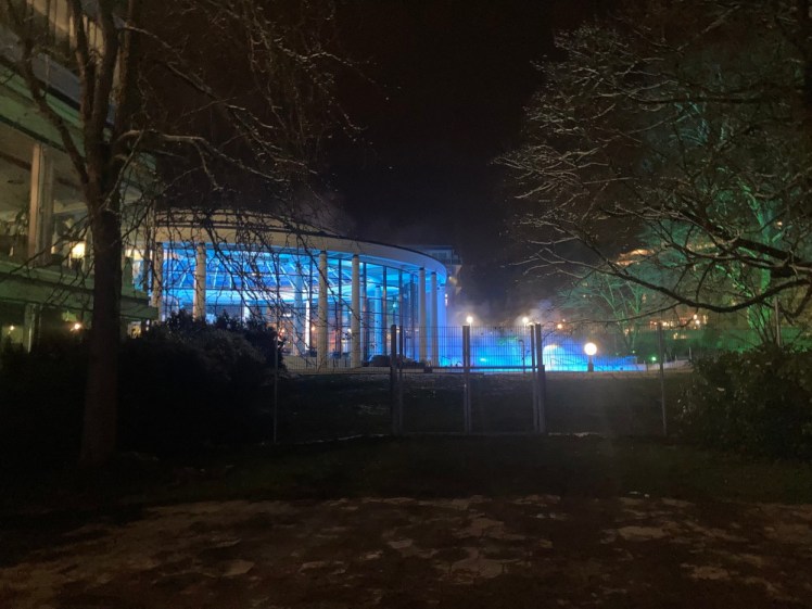 The round building housing the main pool and the steam from the outdoor pools, all lit up in bright blue in the dark.