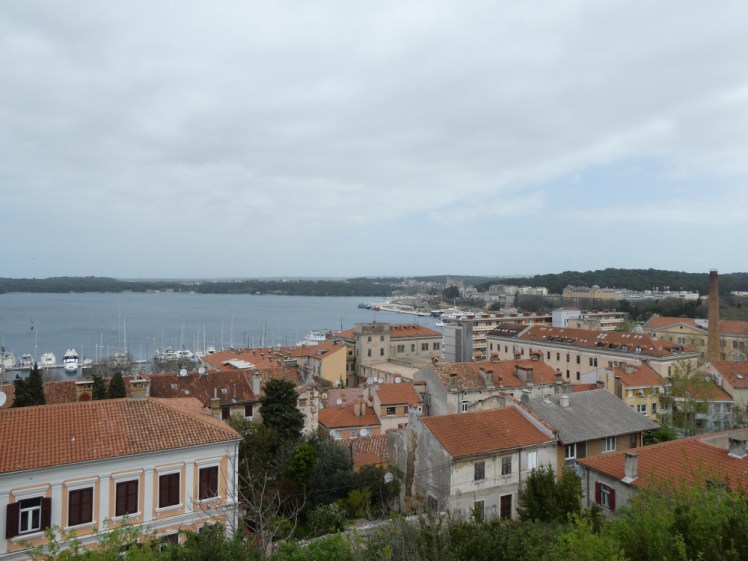 A view north from the fort, looking over the red roofs of Pula, the blue bay and the wooded land beyond.