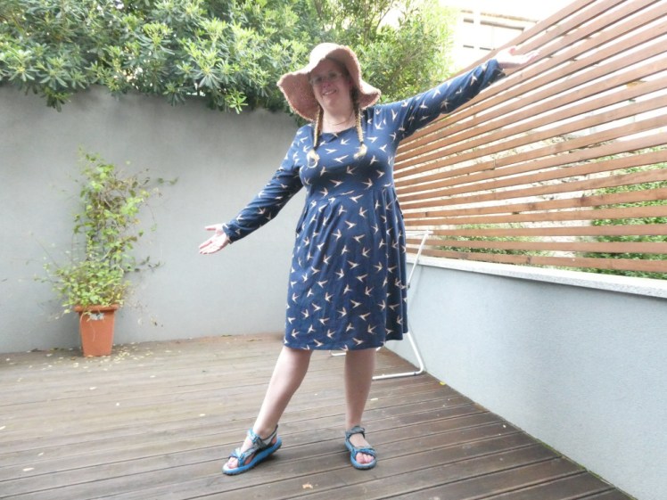 Me holding out my arms as if to show off my knee-length long-sleeved navy dress covered in little birds. This dress has pockets!