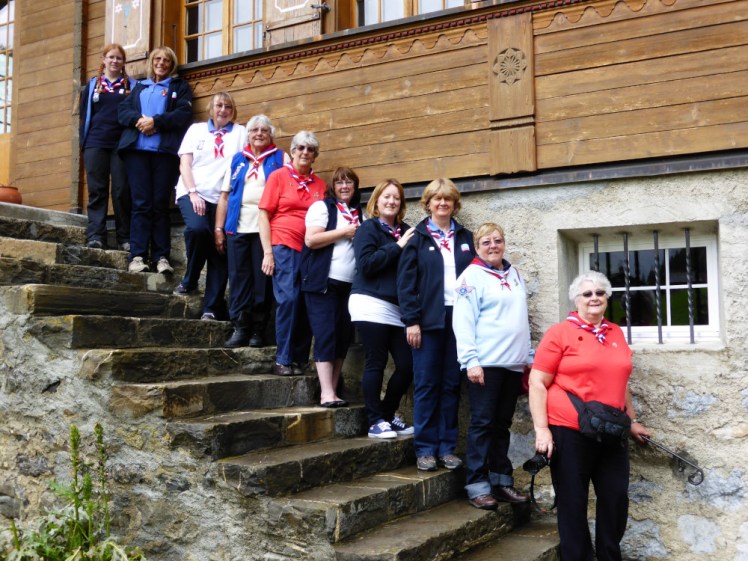 A group photo on the back steps of Our Chalet. We're all wearing variants of either adult leader or Trefoil Guild uniform, so we're all in shades of blue, white and red.
