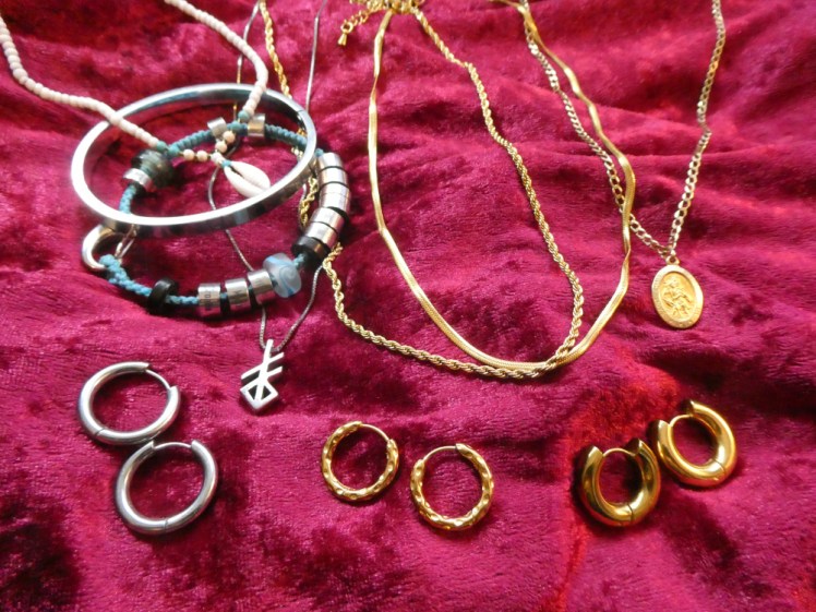My jewellery - an assortment of gold and stainless steel laid out on a piece of red velvet.