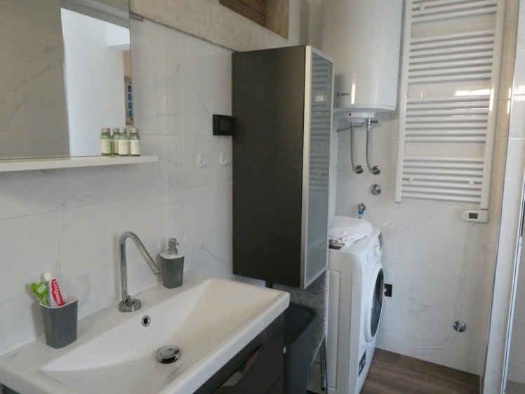 The rest of the bathroom - a big sink with three drawers underneath it (one cut out to fit around the pipes), a tall cabinet and a washing machine.