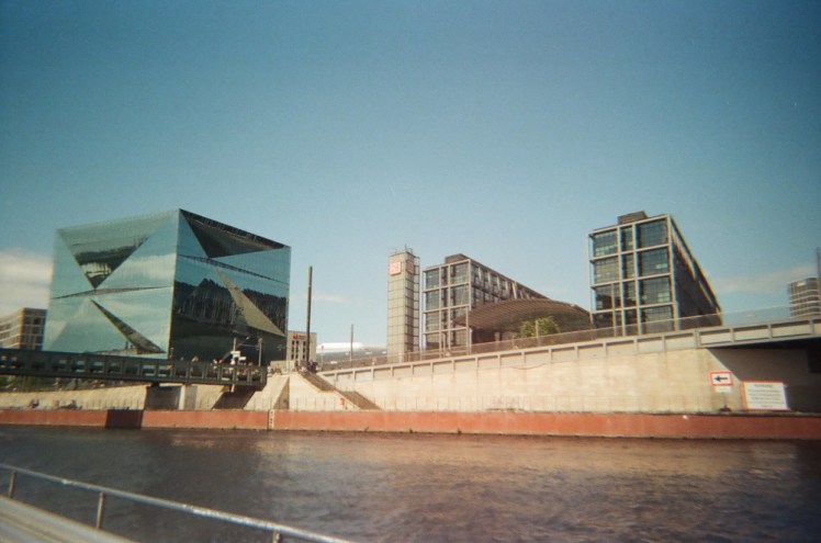 The more modern buildings around the Hauptbahnhof as seen from the river. The glass buildings, blue sky and orange edge to the footpath above the river give it a proper 60s retro-futuristic vibe.