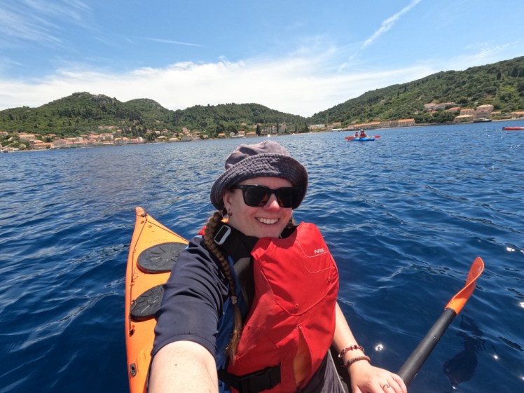 A selfie in an orange sea kayak out in the deep blue water of the coast off Dubrovnik.