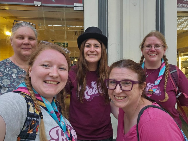 This picture is from last year's Monopoly and it shows my team being the first to find Ms Monopoly. She's the one in the middle with the bowler hat on and I'm rear right. We're both wearing burgundy Rebel t-shirts and I'm wearing a Rebel neckerchief, which is bright blue with burgundy and hot pink double border. Front left, Sammy is wearing the grey Rebel t-shirt with the neckerchief and then Jo and Amanda aren't in "uniform".