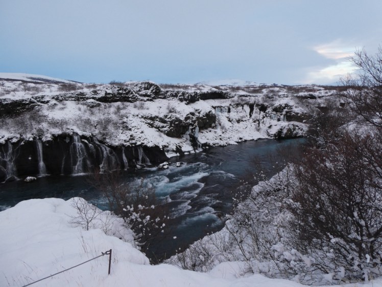 Hraunfossar, a waterfall that pours out of a lava field into a deep teal-blue river. This isn't snowmobiling but if you do this particular trip, you'll probably stop here on the way to the glacier.