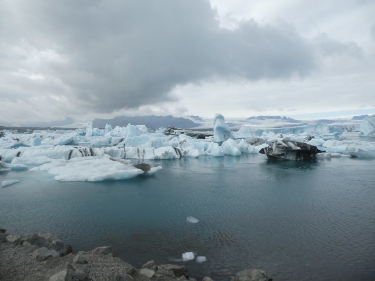 Jökulsárlón, the glacial lagoon, under a heavy grey sky. The lagoon is choked with large blue striped icebergs. Despite the wintery appearance, this was actually taken in August.