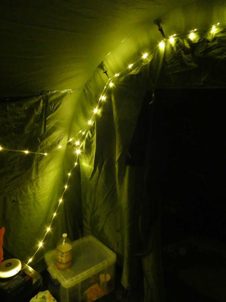 My camping lights strung up inside the tent, leading to the illuminated disc on top of my cupboard. The photo is quite green-tinted because the tent is green. The reality was a lot more yellowy-white.