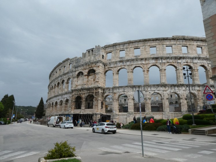 Pula Arena looming over a road, being loomed over by some quite threateninly grey clouds. It's just so big and so old and it's just there as if it's normal to have a Roman amphitheatre down the road.