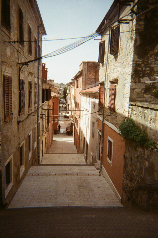 A view down a narrow street which goes down in long gentle steps, making the city look like a bit of sepia-tinted warren.