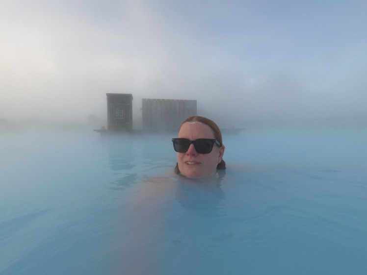 Me swimming in the Blue Lagoon. It's very hazy so you can't see the line between the turquoise water and the sky that's nearly completely blue because of the mist between them. Behind me is one of the hot water intakes and although I'm taking a selfie, this is one of those pictures where you could just about believe I'm not.