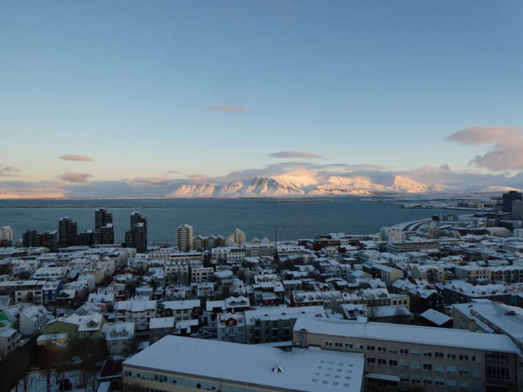 Views across snowy Reykjavik and the bay to where snow-covered Esja gleams in the winter sun, as seen from the top of Hallgrimskirkja's tower.