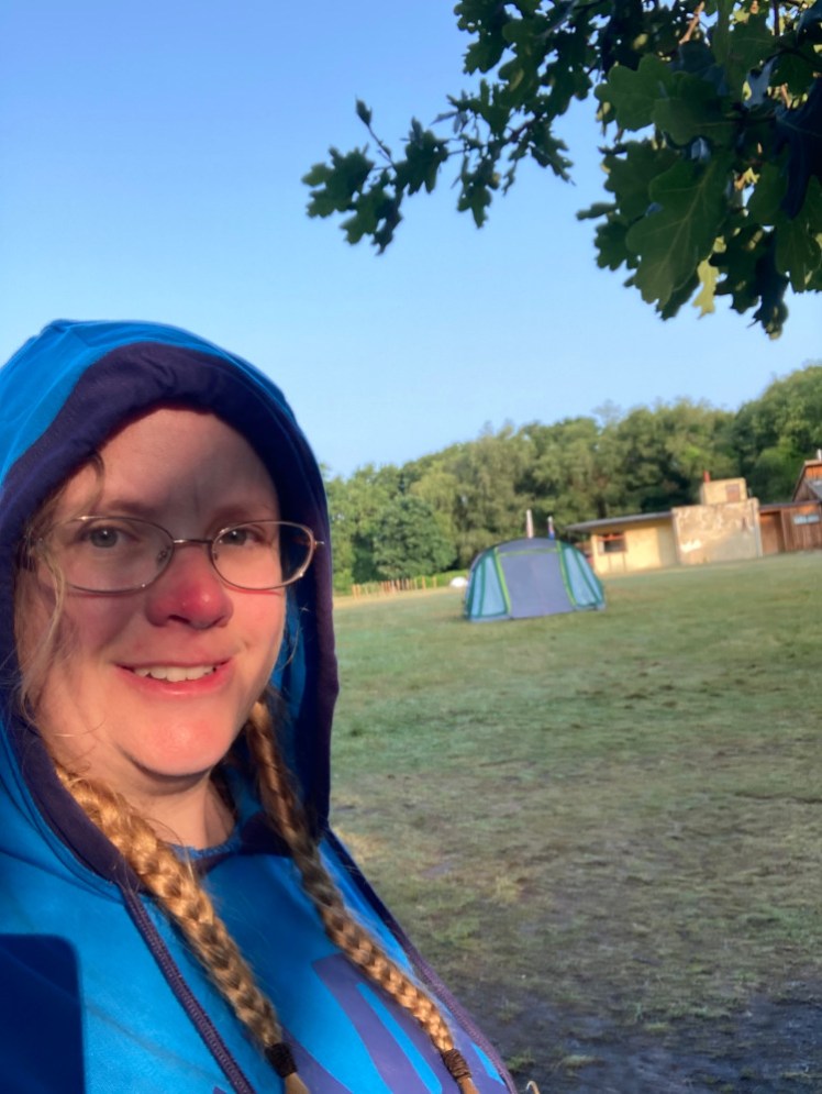 A selfie on Sunday morning, with blue sky behind me and a pink tint on my face from the low morning sun. The ground has dried out a lot behind me.